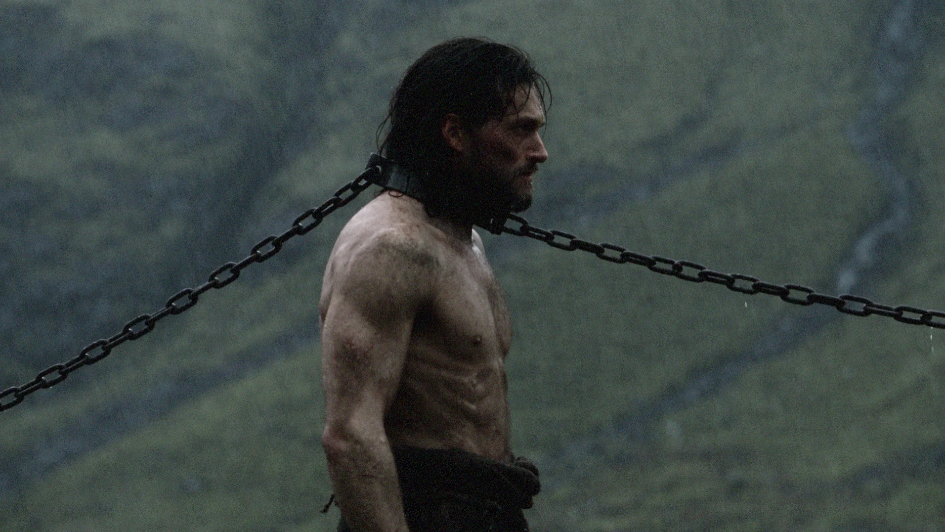 THYMOS protagonist restrained by an iron collar and chains in a cold, fog-covered mountain landscape inspired by circa 1000 BCE.