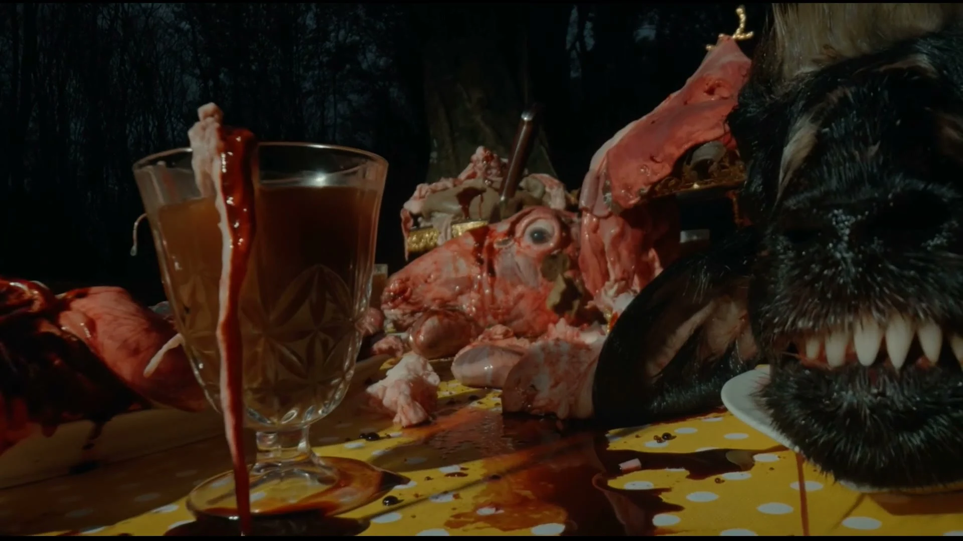 Blair Witch AI visual effects frame: a feast table in the night forest covered in raw flesh, blood and a snarling animal head.
