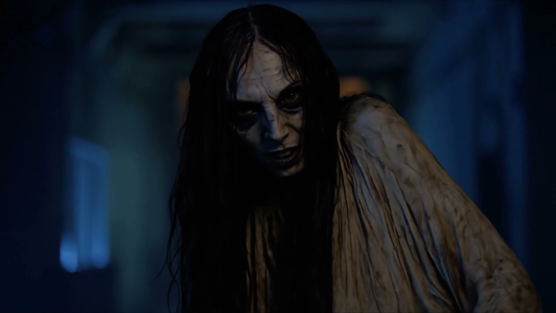 Blair Witch AI VFX frame: a long-haired figure leans toward the camera in a dark blue corridor.