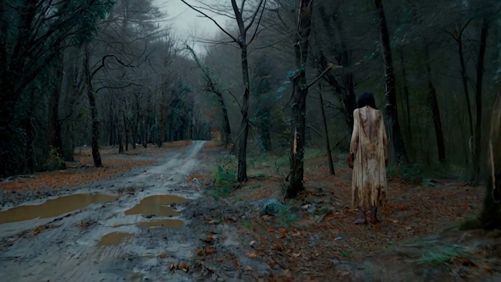 Blair Witch AI visual effects frame: a long-haired figure in a pale dress stands beside a wet forest road.