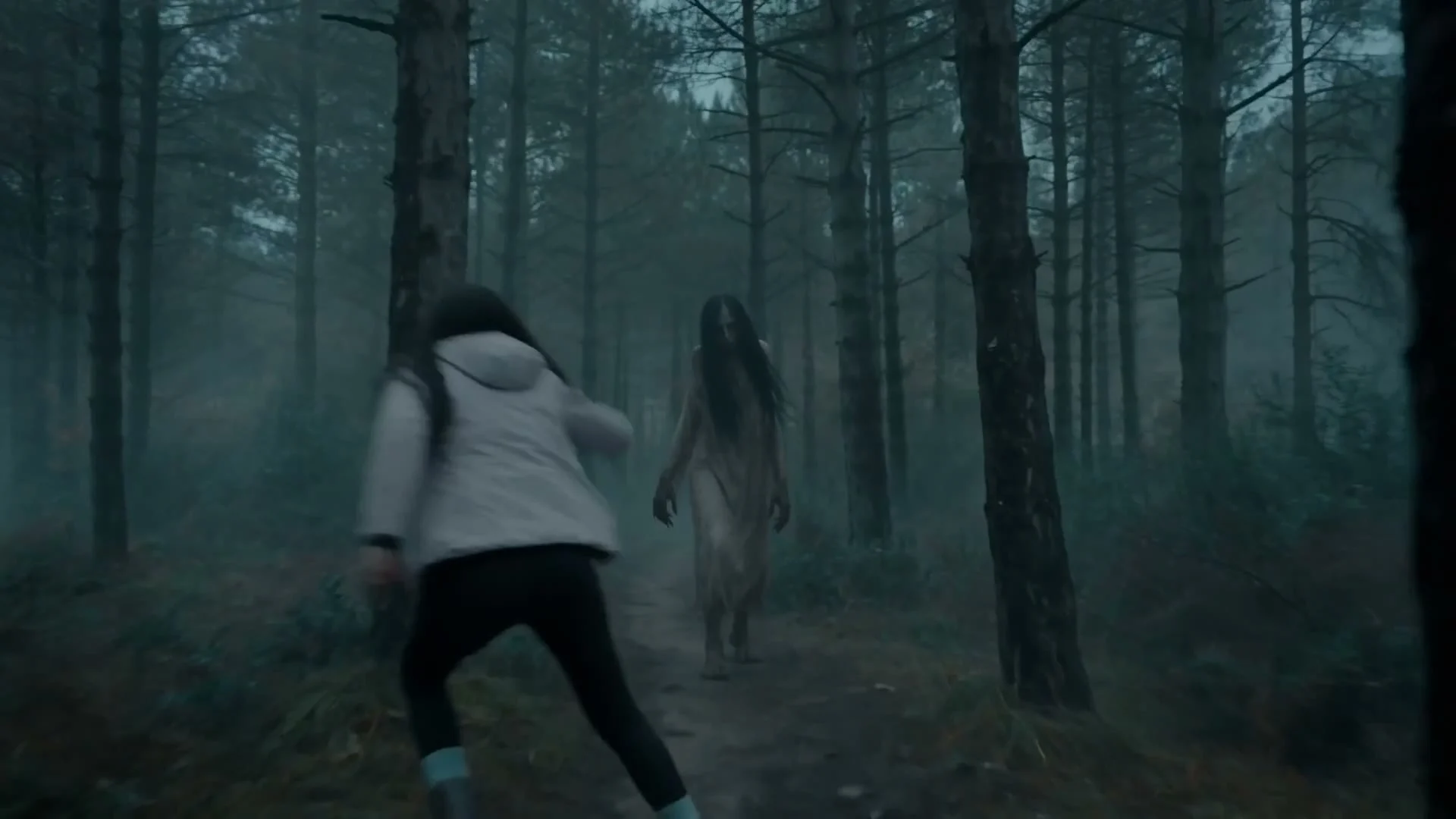 Blair Witch AI visual effects frame: a long-haired figure in a pale dress walks out of the fog between pine trees.